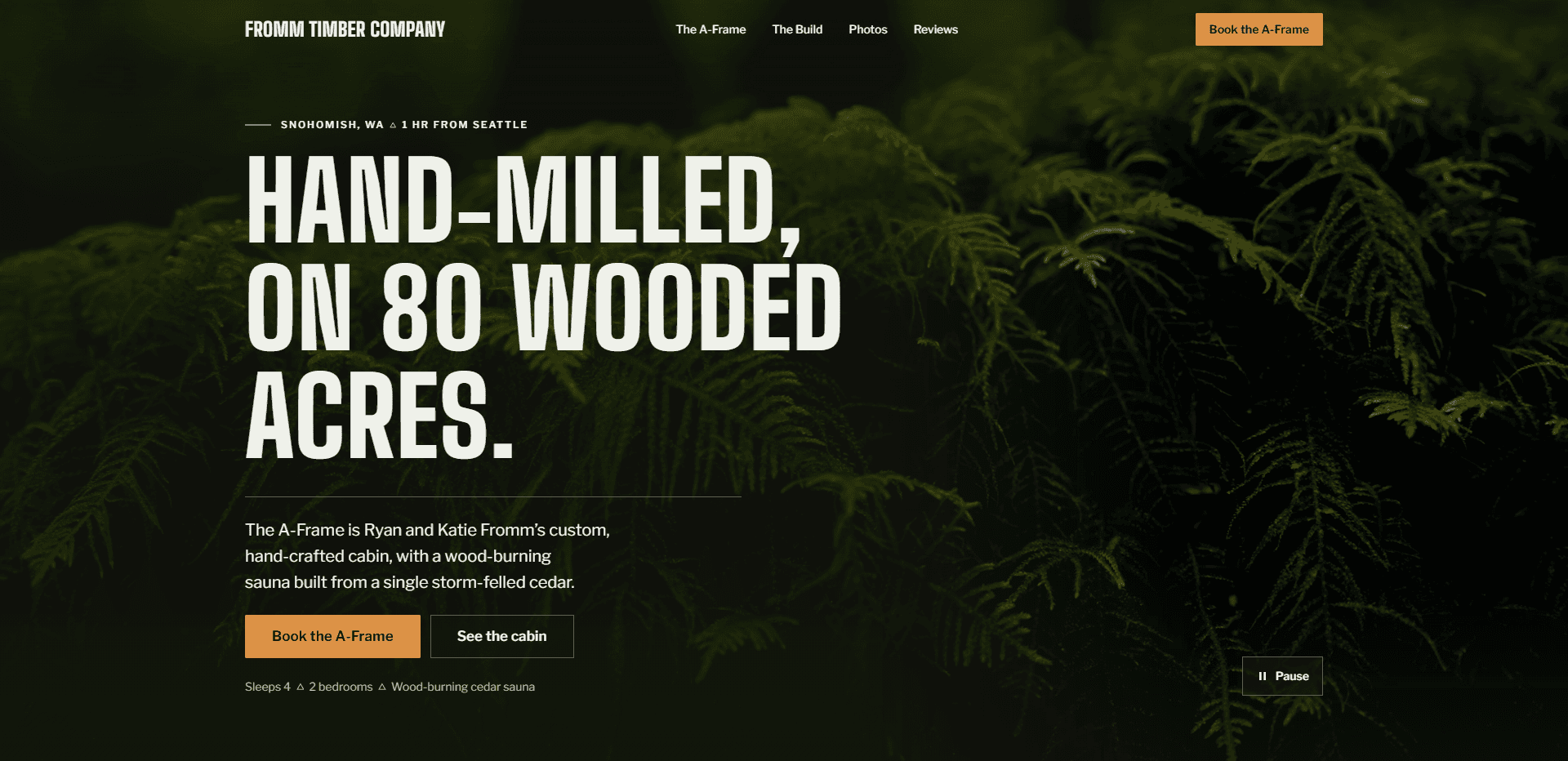 Homepage of Fromm Timber Company: a dark green video still of mossy forest ferns, under a top bar carrying the condensed 'Fromm Timber Company' wordmark, navigation reading The A-Frame, The Build, Photos, and Reviews, and an orange 'Book the A-Frame' button, above the kicker 'Snohomish, WA - 1 hr from Seattle' on a green rule, the oversized condensed capitals headline 'Hand-milled, on 80 wooded acres.', a paragraph about Ryan and Katie Fromm's custom, hand-crafted cabin with a wood-burning sauna built from a single storm-felled cedar, an orange 'Book the A-Frame' button beside an outlined 'See the cabin' button, the line 'Sleeps 4, 2 bedrooms, wood-burning cedar sauna', and a pause control for the background video in the corner.