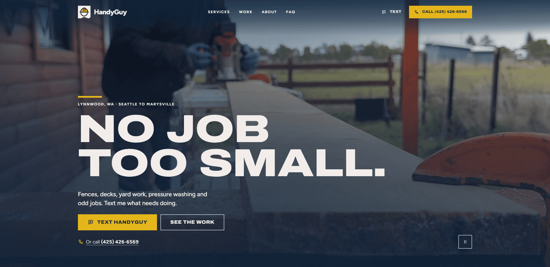 Homepage of HandyGuy: a navy wash over a video still of a gloved worker running a router along a long board on a porch beside a log-sided wall, with a rail fence and open field behind, under a top bar carrying a hard-hat mark beside the 'HandyGuy' wordmark, navigation reading Services, Work, About, and FAQ, a 'Text' link, and a yellow 'Call' phone number button, above a short yellow rule and the kicker 'Lynnwood, WA - Seattle to Marysville', the oversized wide capitals headline 'No job too small.', a line about fences, decks, yard work, pressure washing, and odd jobs, a yellow 'Text HandyGuy' button beside an outlined 'See the work' button, an 'Or call' phone number link, and a pause control for the background video in the corner.