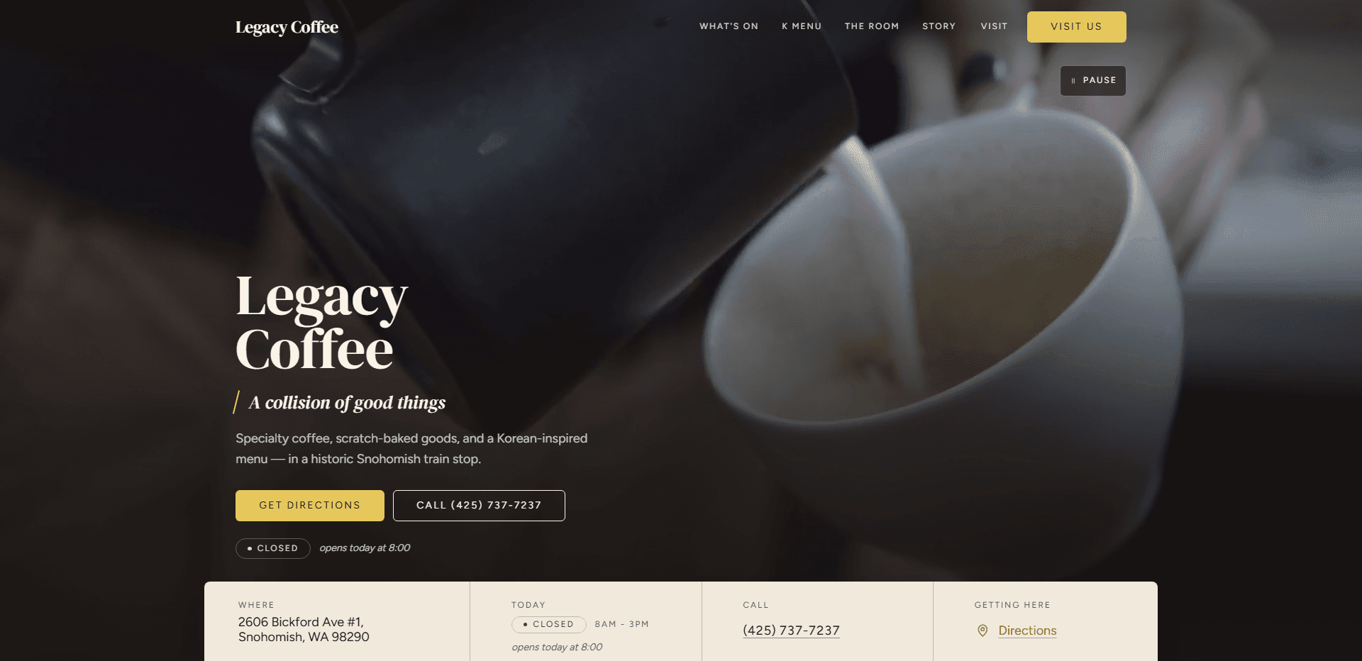 Homepage of Legacy Coffee: a dark, soft-focus video still of a black pitcher pouring steamed milk into a pale ceramic cup, under a top bar carrying the serif 'Legacy Coffee' wordmark, navigation reading What's On, K Menu, The Room, Story, and Visit, a gold 'Visit us' button, and a pause control for the background video beneath it, above the large serif headline 'Legacy Coffee', the italic line 'A collision of good things' set off by a gold slash, a line about specialty coffee, scratch-baked goods, and a Korean-inspired menu in a historic Snohomish train stop, a gold 'Get directions' button beside an outlined 'Call' phone number button, a 'Closed' status pill reading 'opens today at 8:00', and a cream information bar across the bottom listing the Snohomish address, today's hours, the phone number, and a directions link.