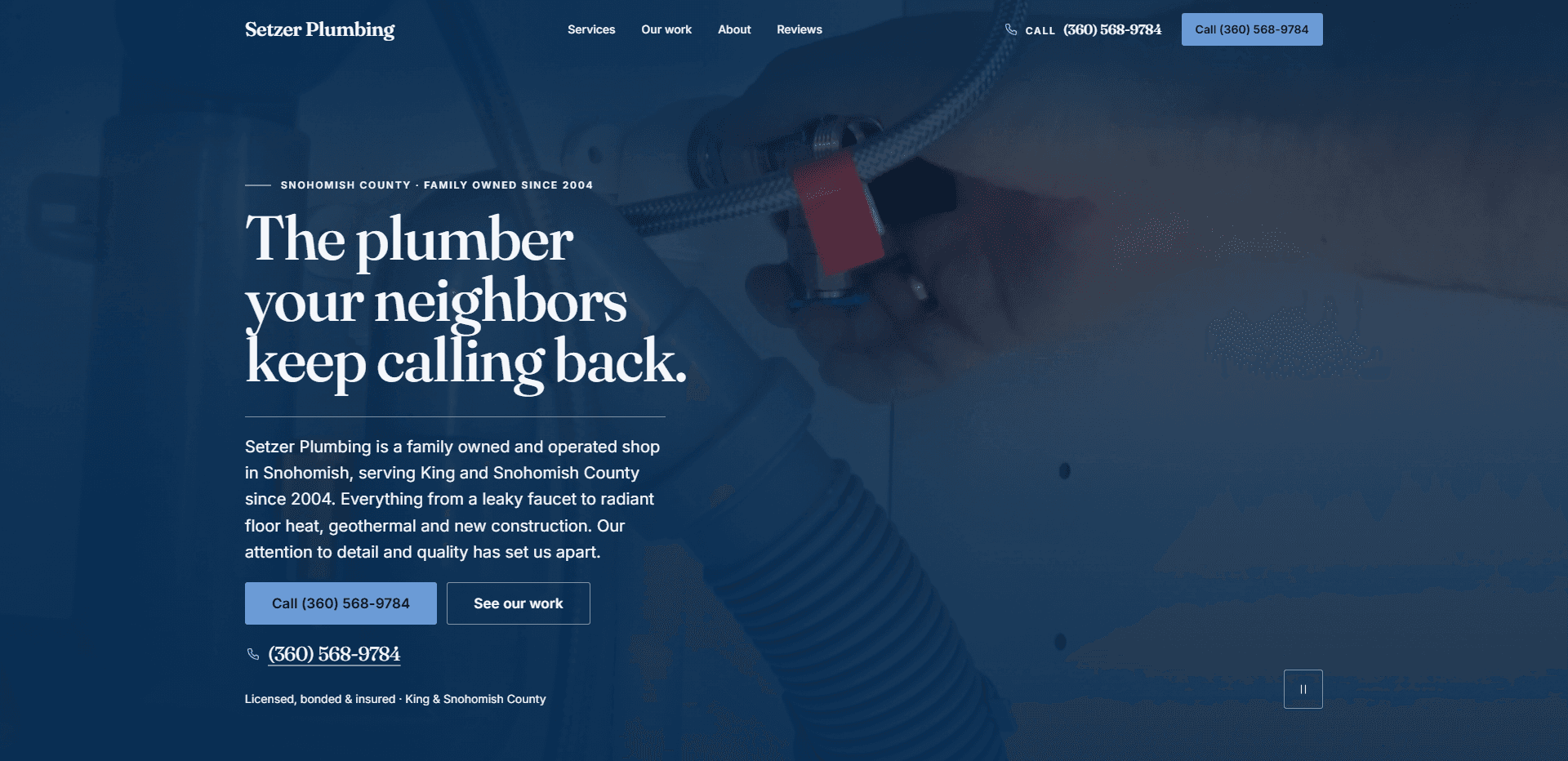 Homepage of Setzer Plumbing: a deep navy wash over a close-up video still of a hand holding a braided steel supply line and a fitting wrapped in red tape above a ribbed drain hose, under a top bar carrying the serif 'Setzer Plumbing' wordmark, navigation reading Services, Our work, About, and Reviews, a 'Call' phone number, and a light blue phone number button, above the kicker 'Snohomish County - Family owned since 2004' on an amber rule, the large serif headline 'The plumber your neighbors keep calling back.', a paragraph about a family owned and operated shop in Snohomish serving King and Snohomish County since 2004, from a leaky faucet to radiant floor heat, geothermal, and new construction, a light blue 'Call' button with the phone number beside an outlined 'See our work' button, the phone number repeated in large serif type, the line 'Licensed, bonded & insured - King & Snohomish County', and a pause control for the background video in the corner.