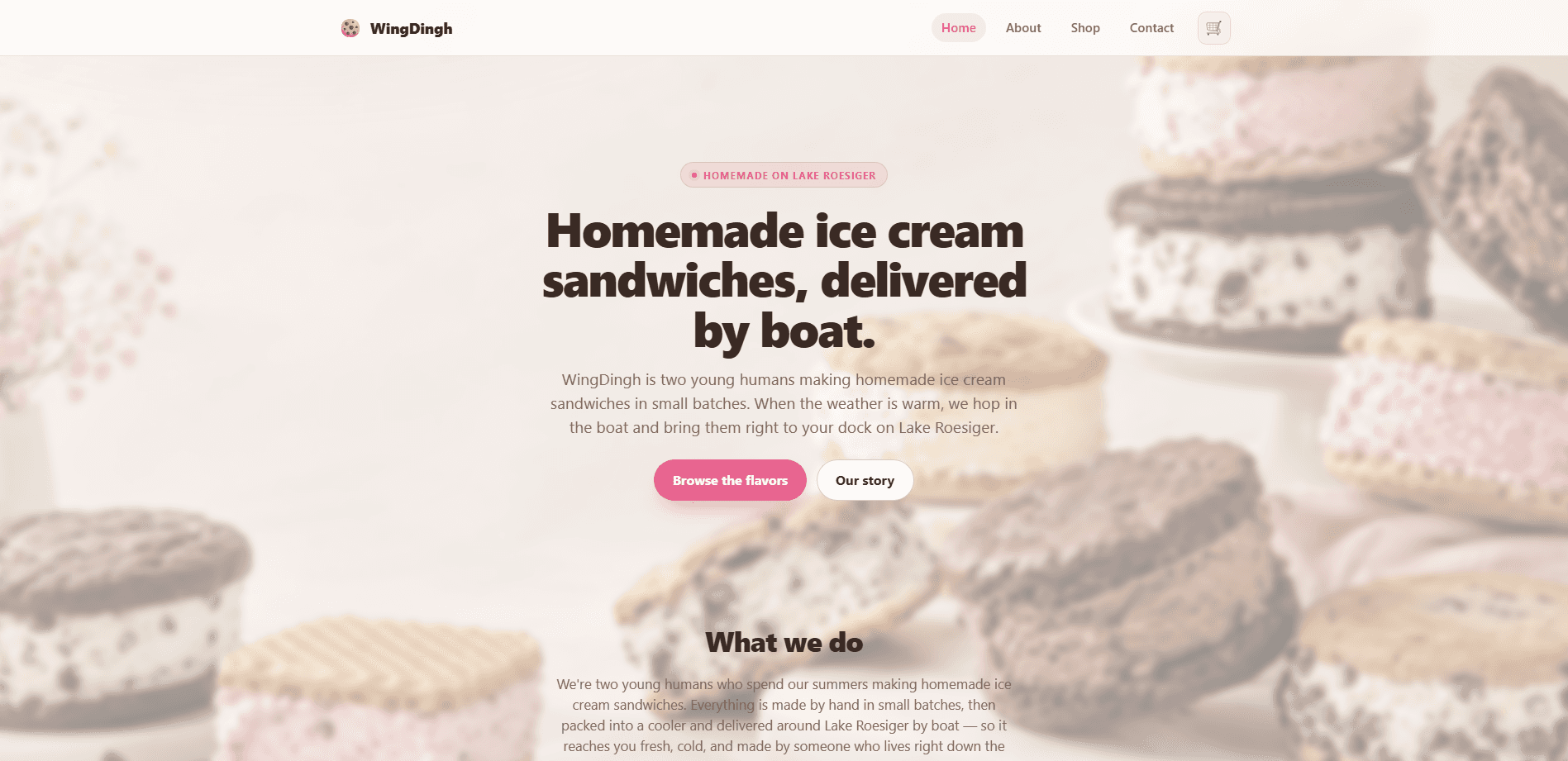 Homepage of WingDingh: a pale cream page over a soft-focus photograph of stacked homemade ice cream sandwiches, with a cookie mark beside the wordmark, navigation reading Home, About, Shop, and Contact beside a cart button, a pink 'Homemade on Lake Roesiger' pill, the heavy headline 'Homemade ice cream sandwiches, delivered by boat.', a line about two young humans making them in small batches and bringing them by boat to docks on Lake Roesiger, and 'Browse the flavors' and 'Our story' actions.